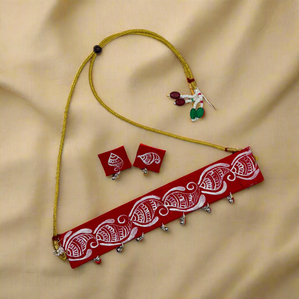 Red and white patterned belt with gold accents, earrings, and a yellow cord on a white background