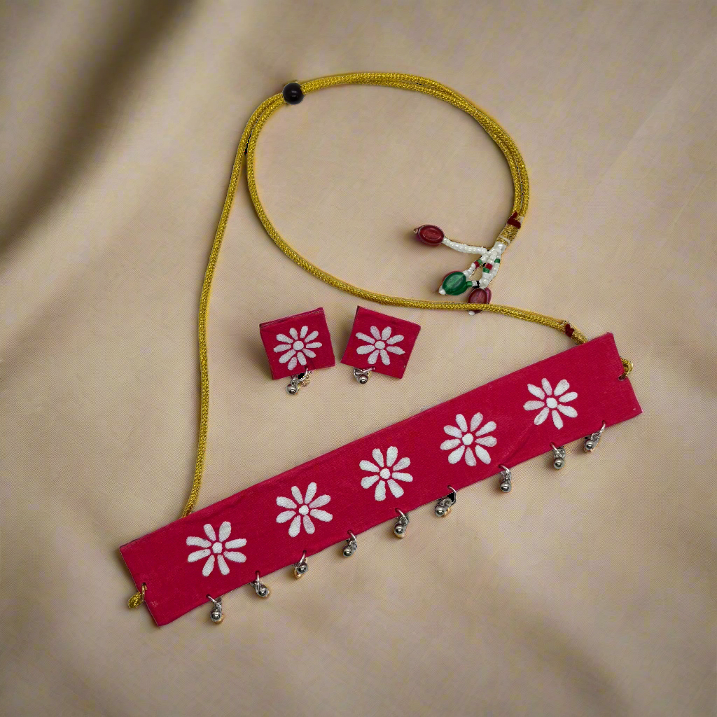 Jewelry set with red necklace and earrings featuring white floral designs on a white background