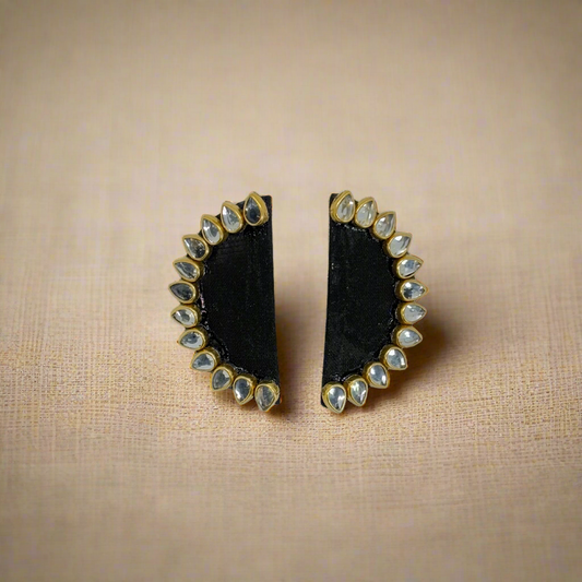 Pair of black earrings with gold and clear stone accents on a white background