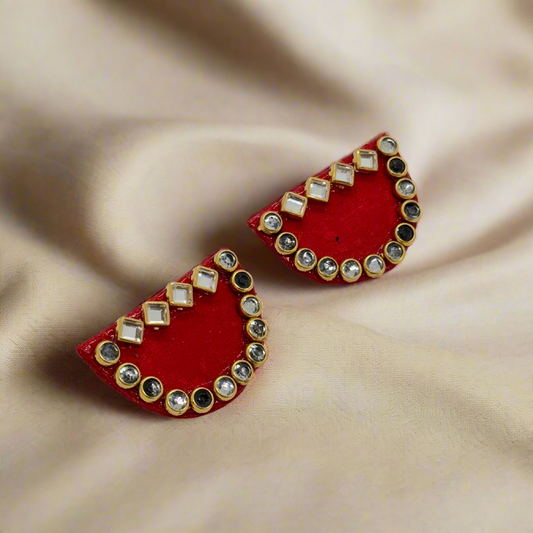 Red earrings with gold and clear gemstone accents on a white background