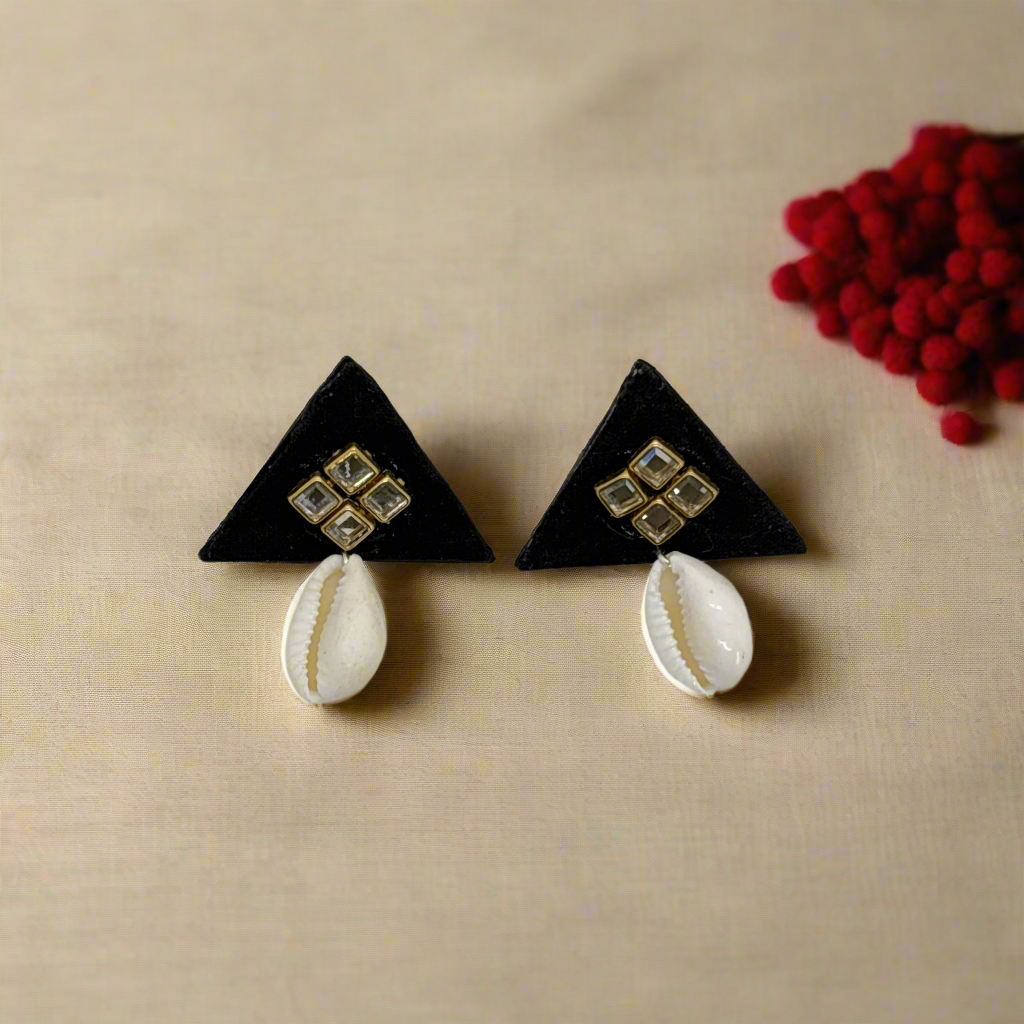 Black triangle earrings with white shell accents on a light gray background