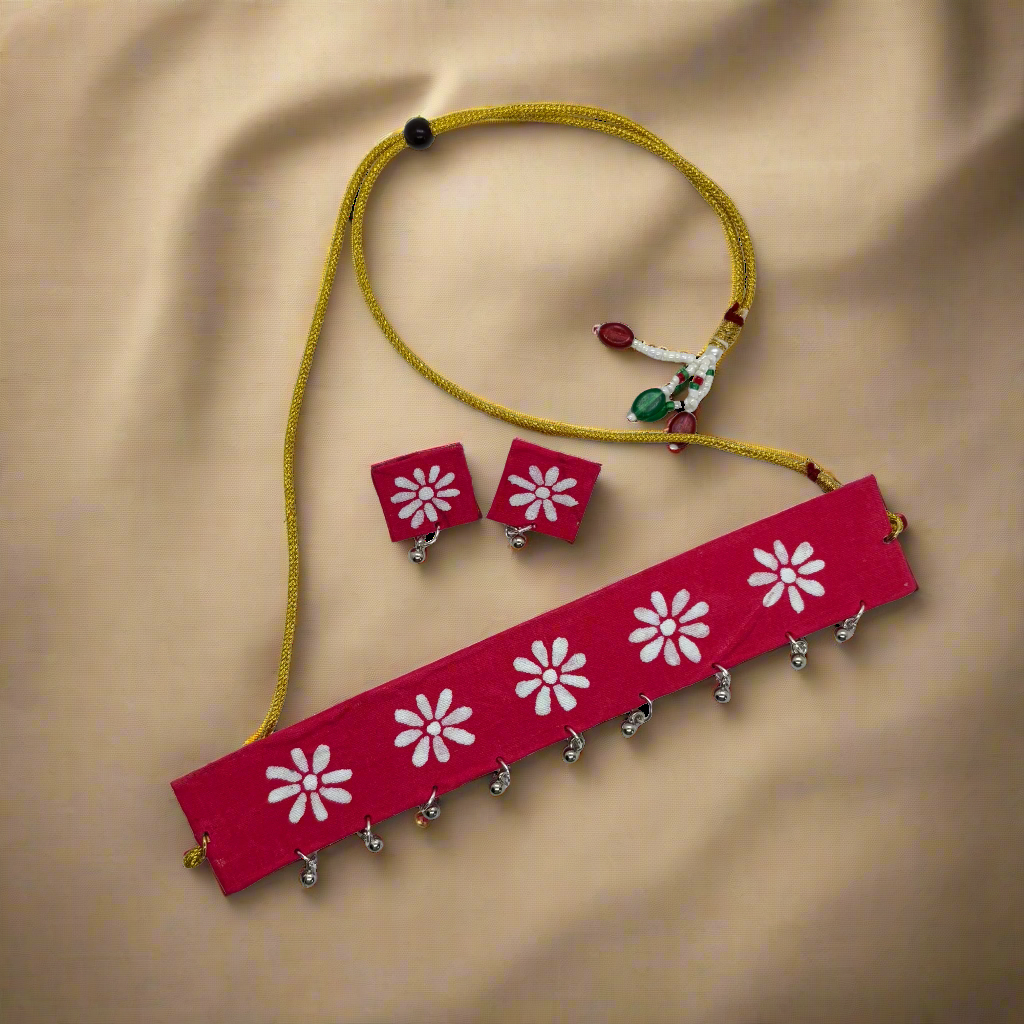 Red headband with white floral patterns, earrings, and a yellow cord on a white background