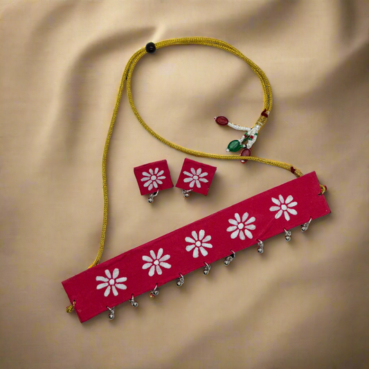 Red headband with white floral patterns, earrings, and a yellow cord on a white background