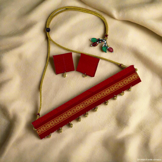 Decorative red fabric with gold patterns and gold beads on a white background