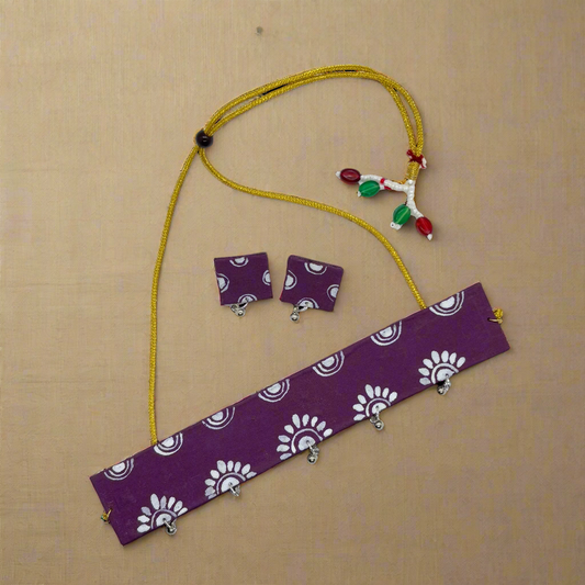 Jewelry set with purple fabric strip, yellow necklace, and earrings on a white background