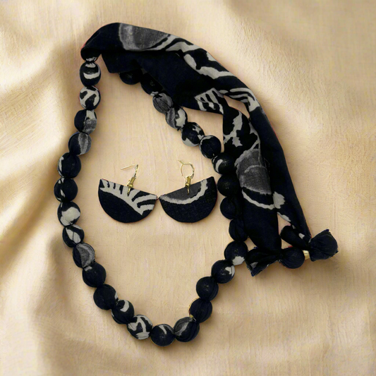Black and white beaded necklace, earrings, and headband set on a white background