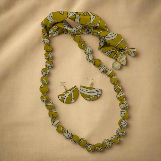 Jewelry set with necklace, earrings, and headband featuring yellow and white pattern on a white background